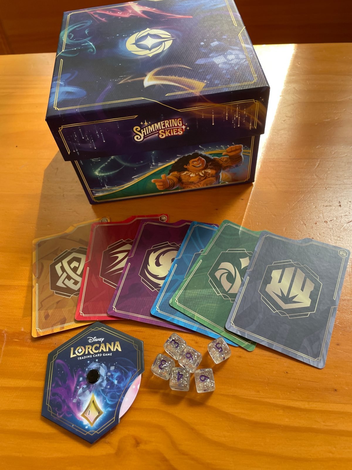 The Disney Lorcana Shimmering Skies Illumineers Trove contents on a wooden table